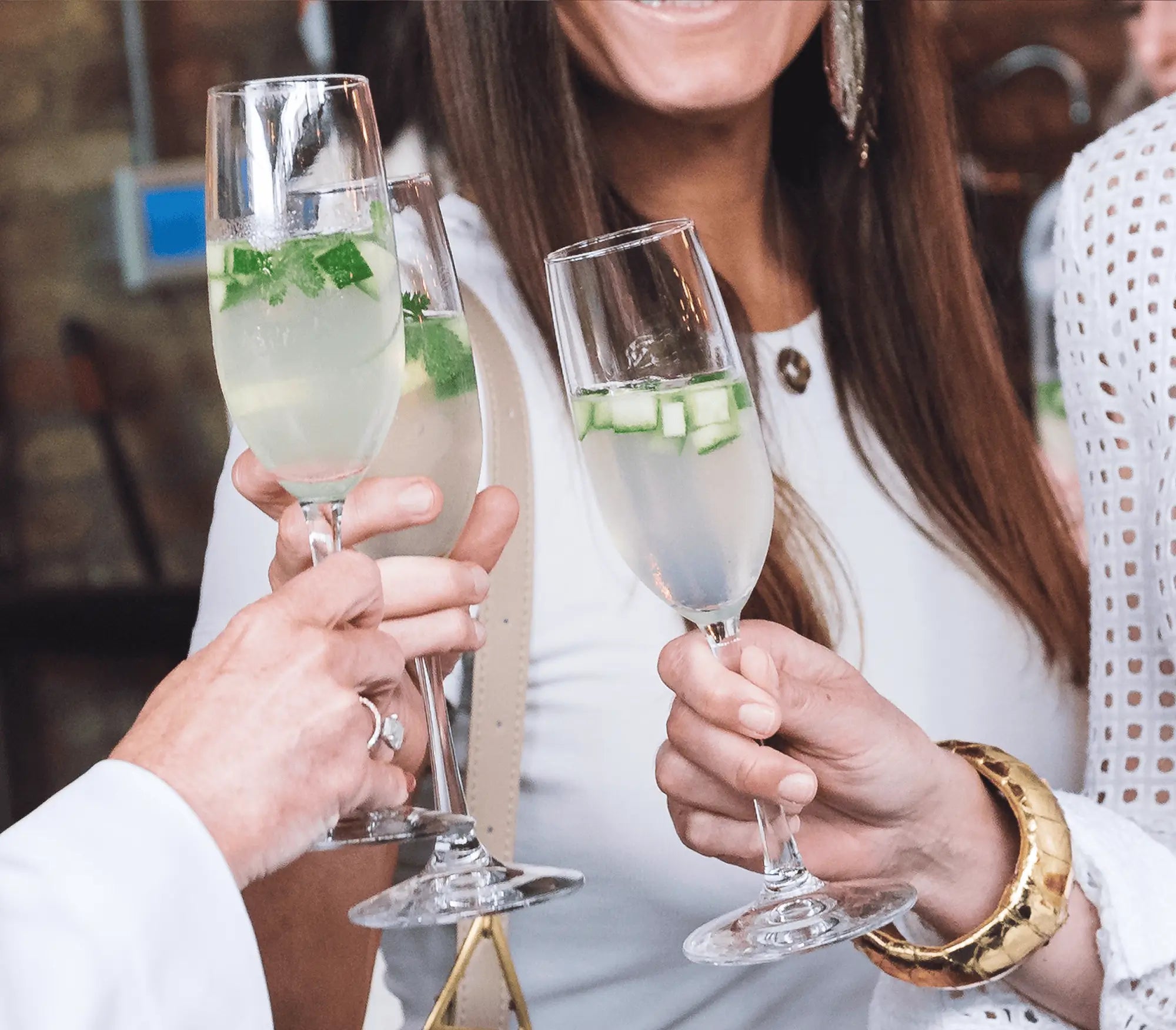 Two people clinking Inspiro Tequila Cocktail glasses with a blurred background
