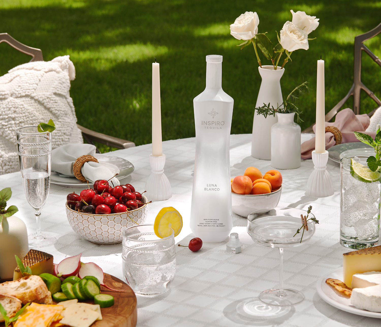 Inspiro Tequila bottle on an outdoor table with food and drinks.