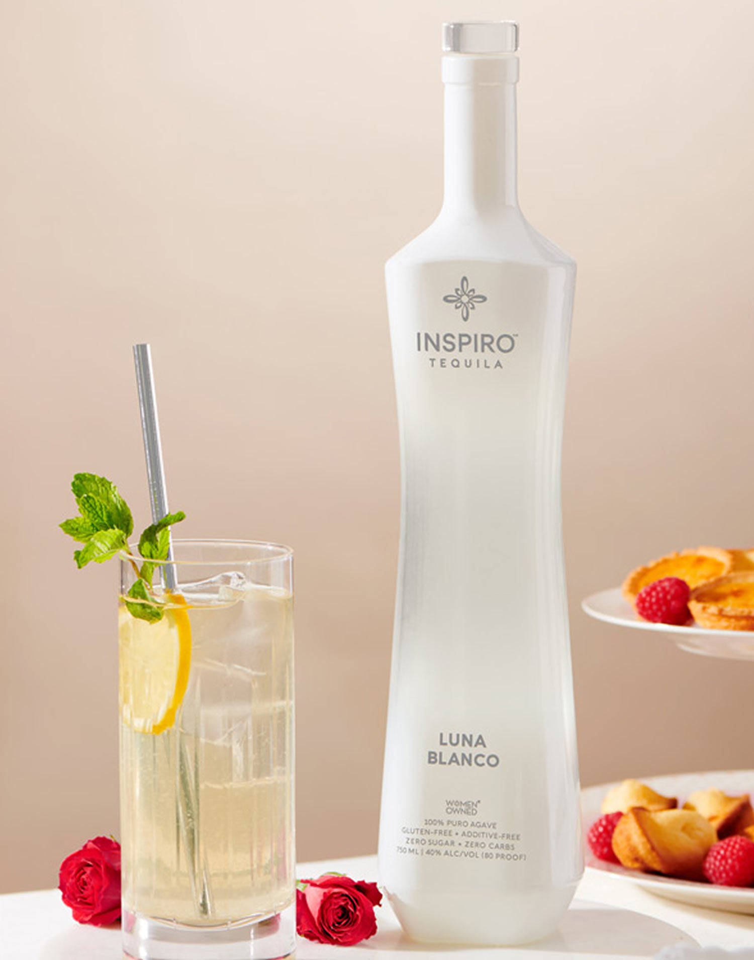 Frosted Inspiro tequila bottle with a cocktail and fruit on a neutral background