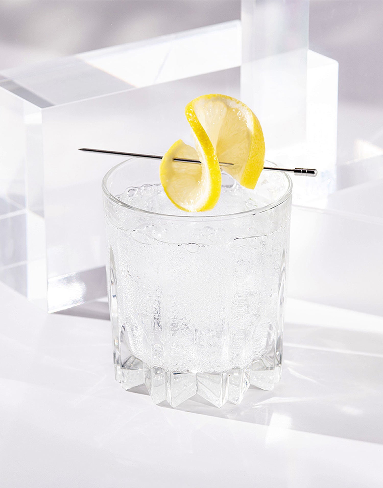 Inspiro Tequila cocktail in a clear glass with a lemon wheel on a white background.