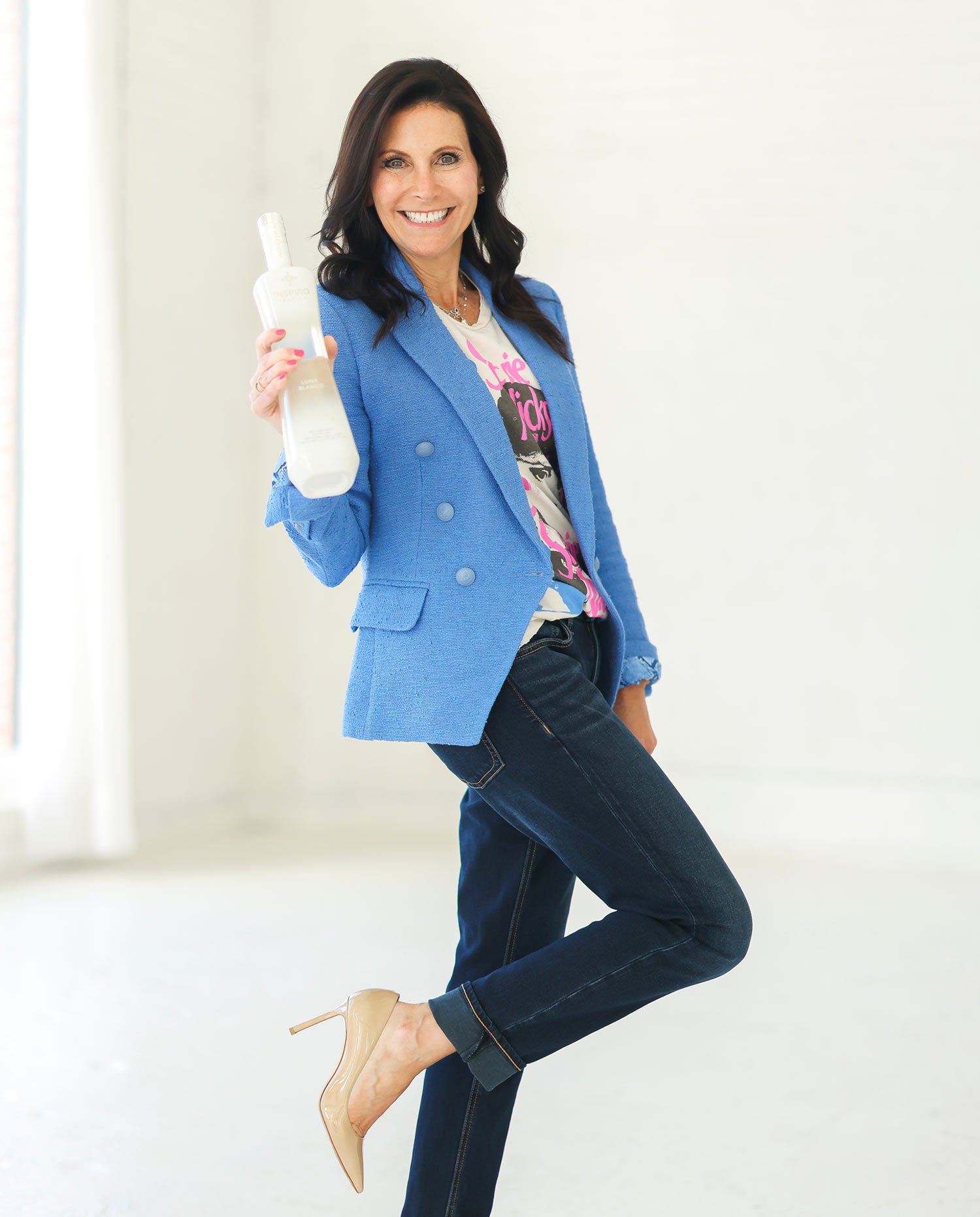 Founder Mara Smith in blue blazer holding a bottle in a bright room