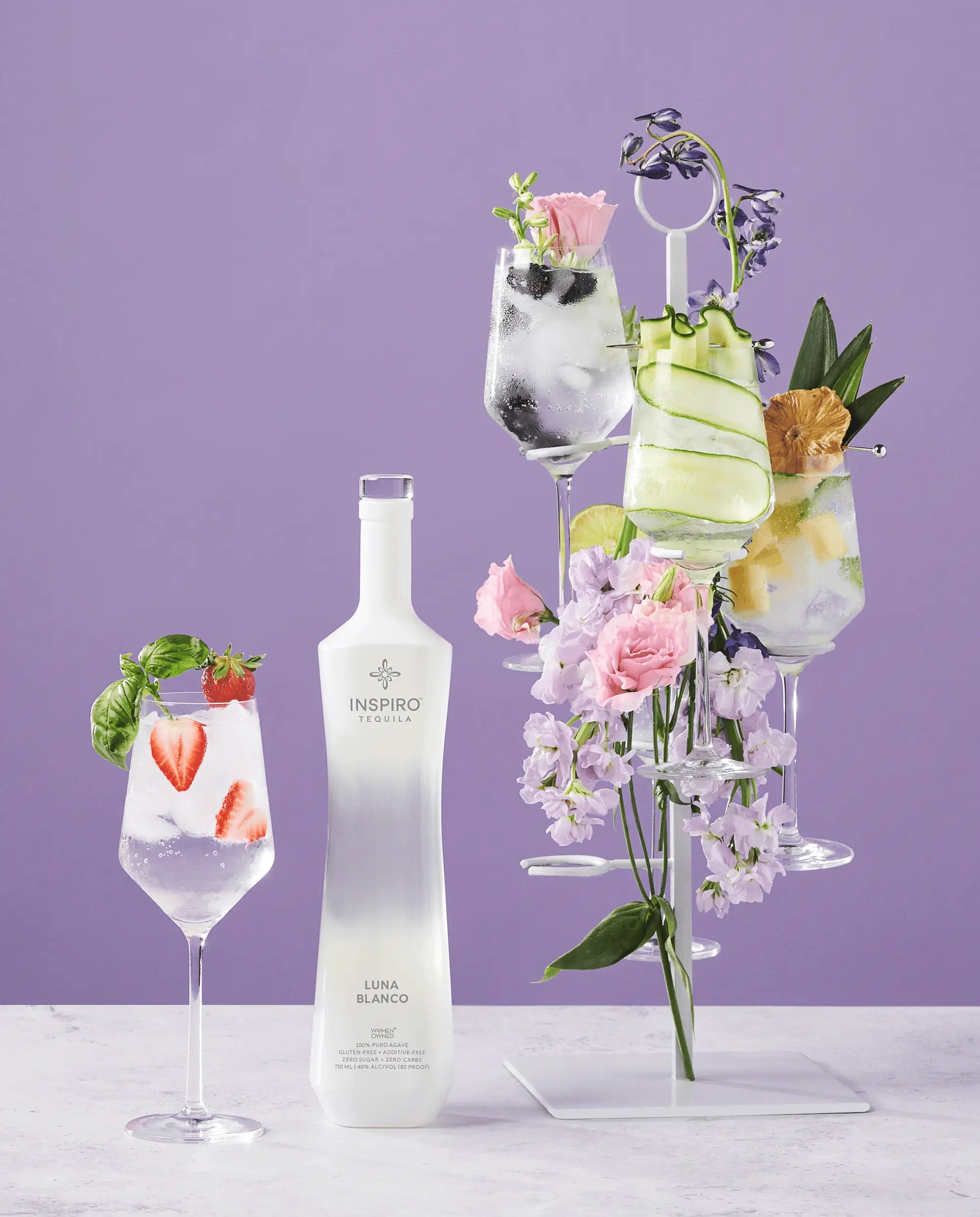 Inspiro Tequila Luna Blanco bottle with floral cocktails on a purple background